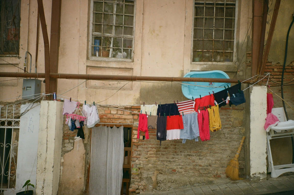 A clothes line outside of a building with a car parked next to it